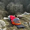 matelas gonflable et sac de couchage Personne installé confortablement dans sont duvet assis sur sont matelas gonflable au bord d'une montagne.