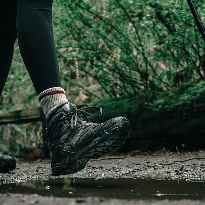 Pieds de trekkeur sur un sentier boueux, bien protégés pour éviter les ampoules