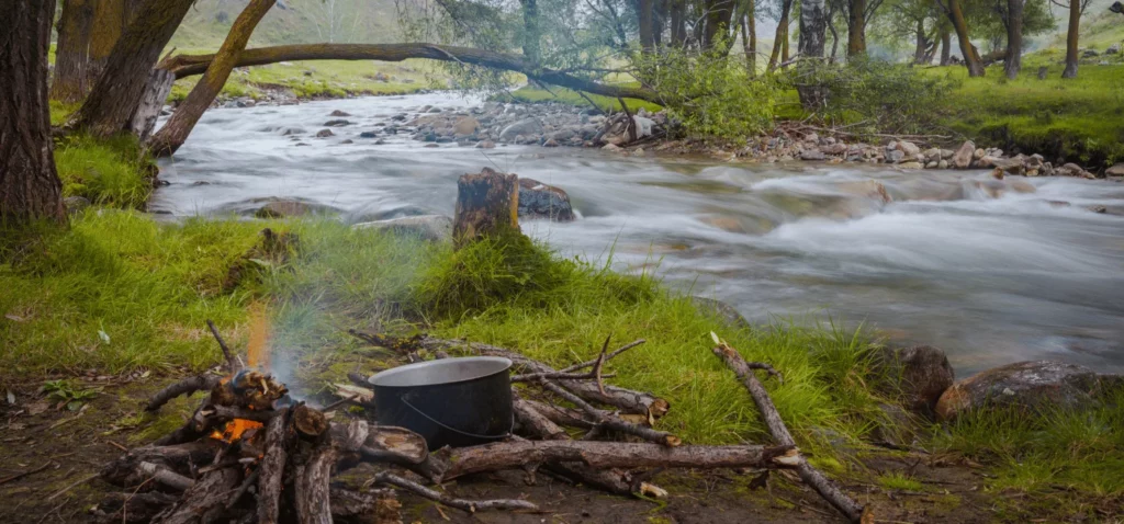 Feu en bivouac près d'une rivière, essentiel pour cuisiner dans un environnement naturel préservé