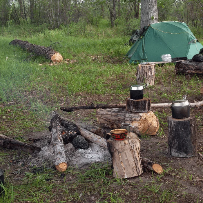 Campement avec feu en bivouac, matériel de cuisine en pleine nature pour une expérience de camping responsable