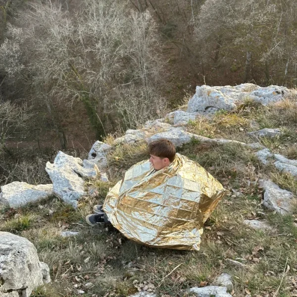 personne se couvrant le corps avec une couverture de survie