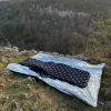 un matelas gonflable à la bouche avec dessous une couverture de survie
