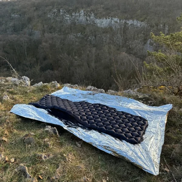 un matelas gonflable à la bouche avec dessous une couverture de survie