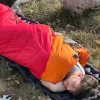 personne qui fait un dodo dans un duvet sur un matelat de bivouac lors d'un trek