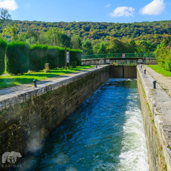 Vue sur une écluse ou l'eau est bien bleu avec au tour des arbres bien taillé