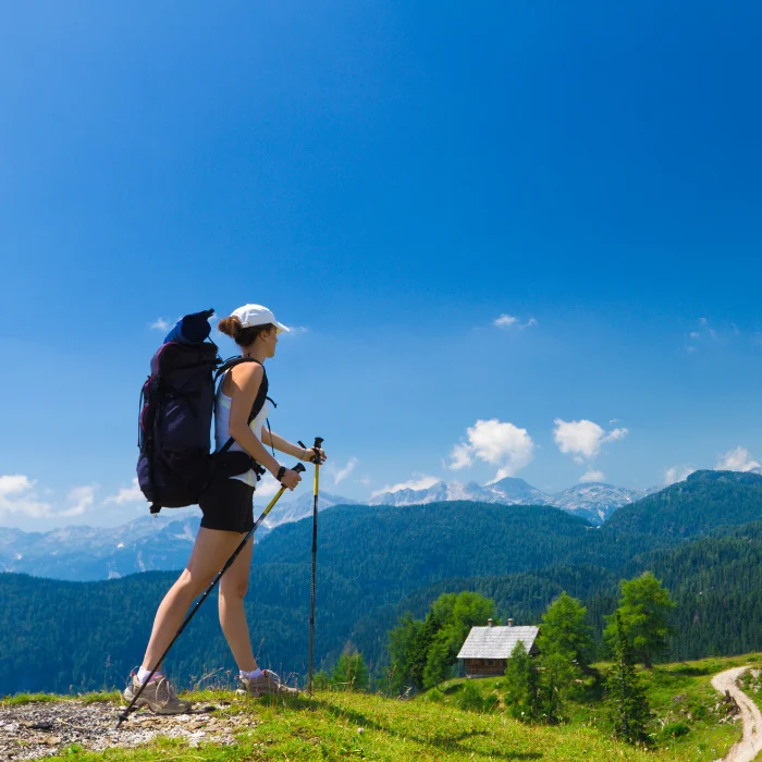 une fille avec un gros sac de trek dans le dos en rando dans les montagnes