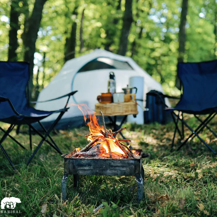 en fond une tente avec 2 chaise de camping et un jolie feu de bois au centre
