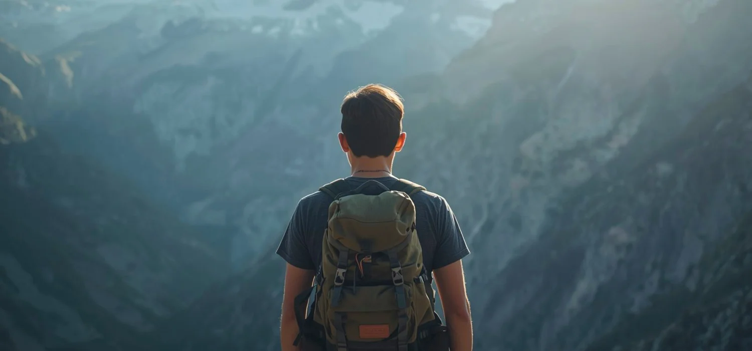 un monsieur au centre avec sont sac de rando contemplant une superbe vue sur une énorme montagne