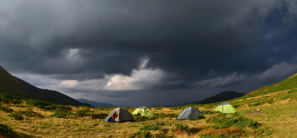 grosse tempe en pproche dans les montagnes avec au centre des tentes de trek installé