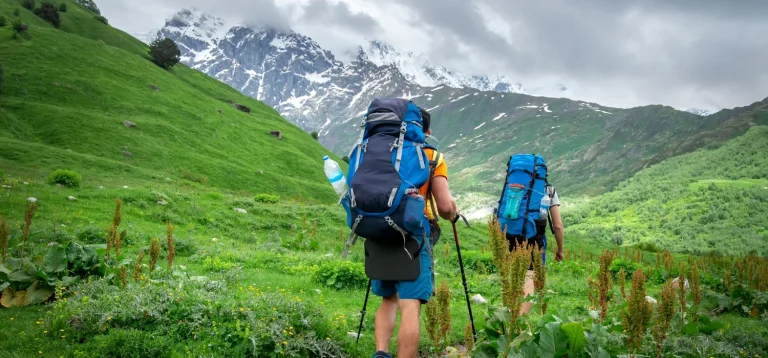 2 personnes en train de marcher avec du matériel pour bivouaquer