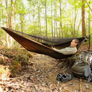 homme avec ses écouteur qui profite dans sont hamac en pleine foret