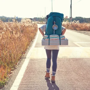 Femme marchant avec un grand sac dessus attaché un matelas gonflable