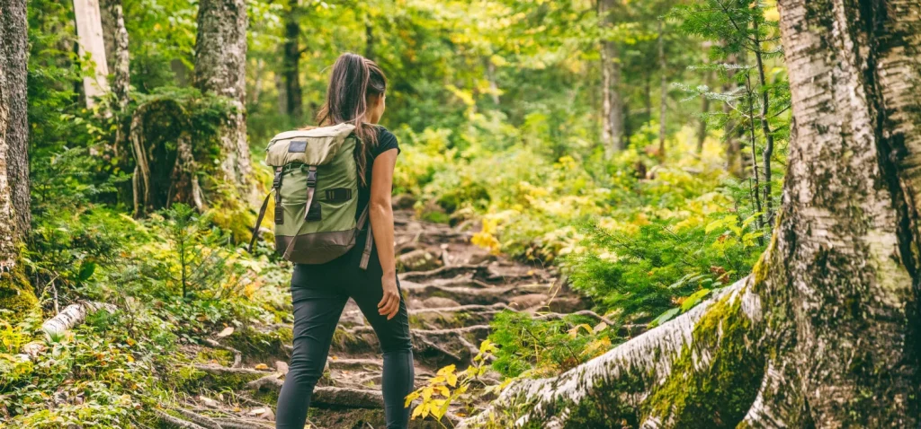 Femme marchant dans une forêt verdoyante.