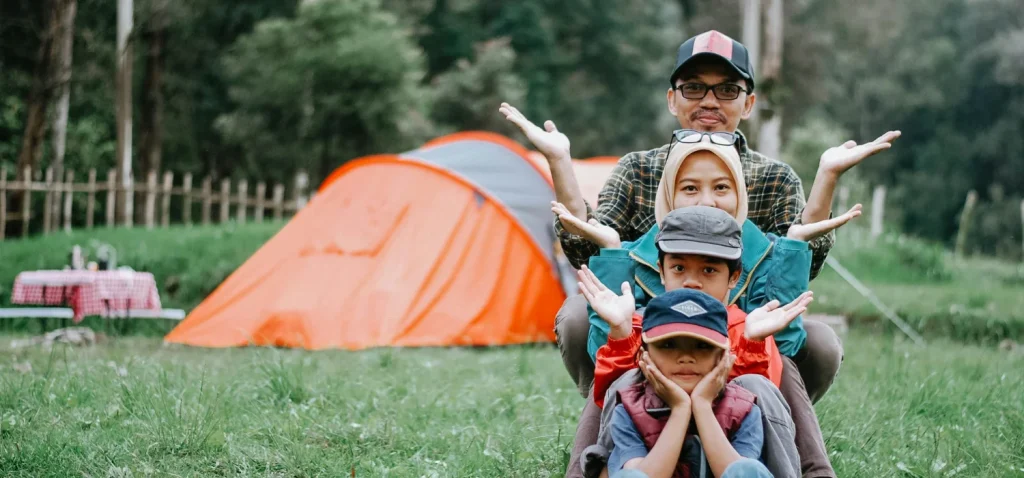 Famille devant une tente orange.