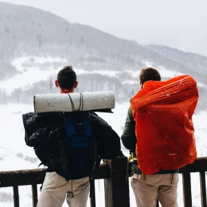 deux personnes regardant le paysage blanc avec des gros sac à dos de bivouac